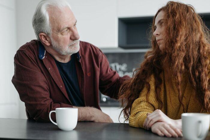 A senior man talking seriously with a young woman in a kitchen