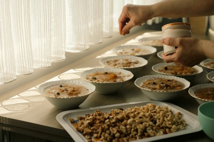 A person garnishing several bowls of traditional dessert