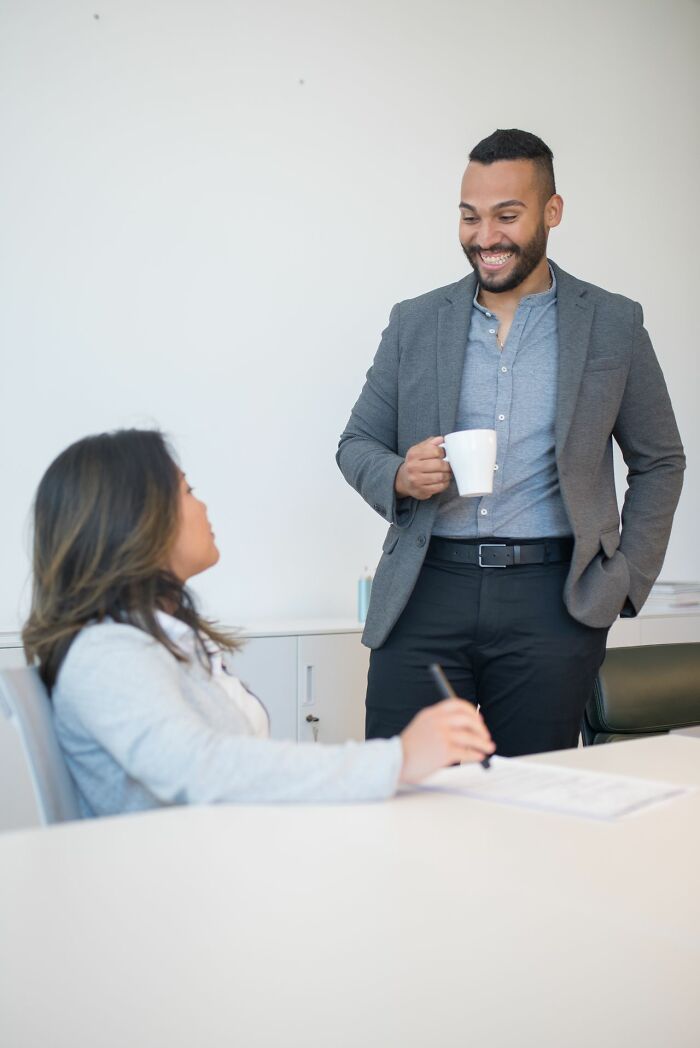 A man and a woman talking in an office, illustrating interactions with male coworkers.
