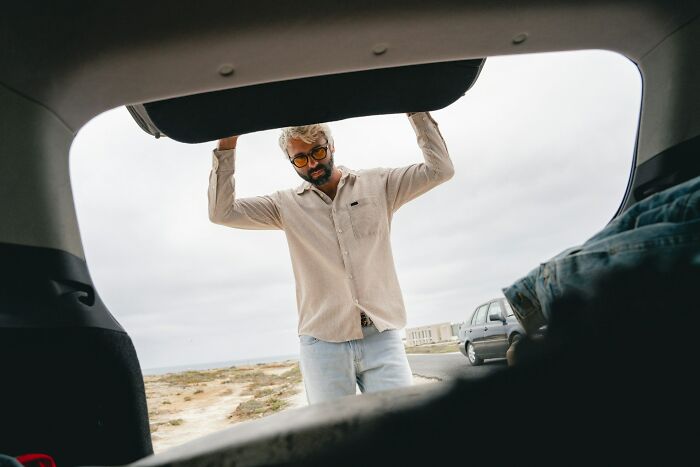 A man looking into the trunk of a car, representing the experiences of women and male coworkers.