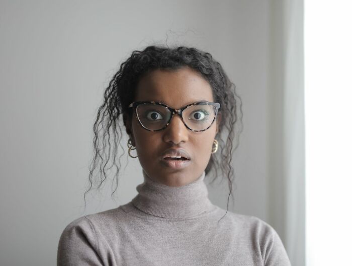 A shocked woman with wide eyes, illustrating reactions to what male coworkers say in the office.