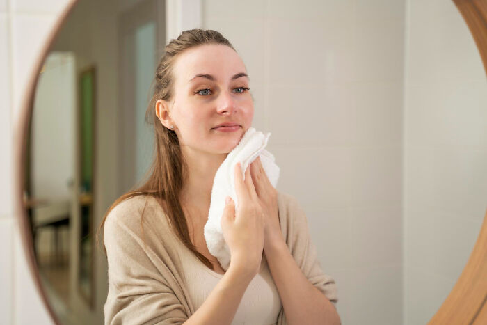Woman wiping her face in a mirror, hiding creepy things people did to a partner.