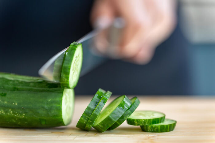 A person slicing a cucumber on a cutting board, related to creepy secrets.