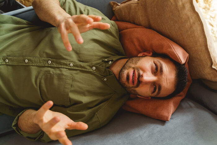 Man lying down gesturing in disbelief over creepy things people did to a partner.