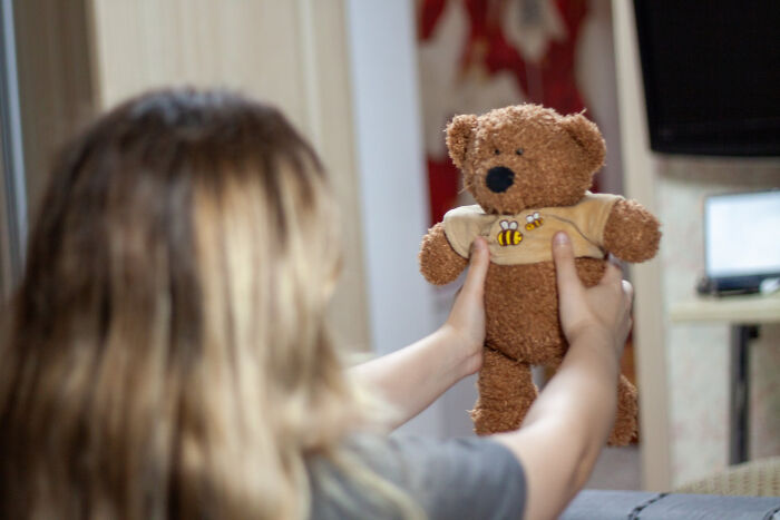 A person holding a small teddy bear, representing secrets people never plan to confess.