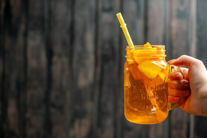 A hand holding a mason jar filled with a yellow drink, hinting at creepy things hidden from a partner.
