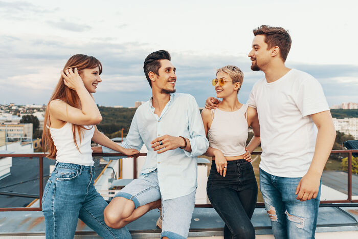 Four smiling friends talking on a rooftop, sharing secrets people did to a partner.