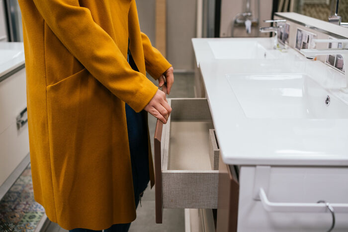 A person opens a bathroom vanity drawer, symbolizing searching for creepy things people did.