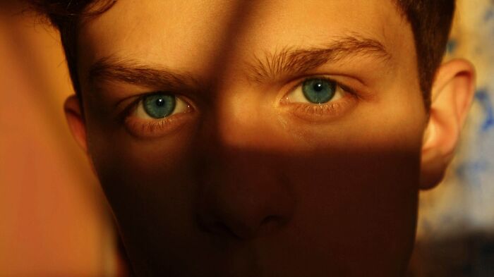 Close-up of a young man with bright blue eyes, symbolizing hidden secrets a partner did to them