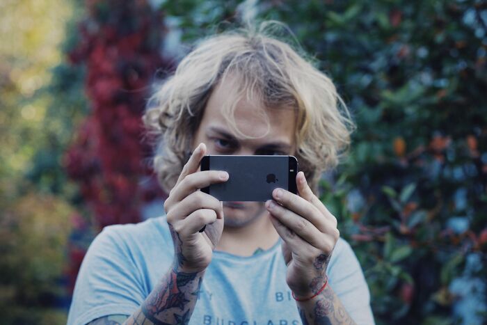 A blonde man holding a phone horizontally to spy, hinting at creepy things people did to a partner