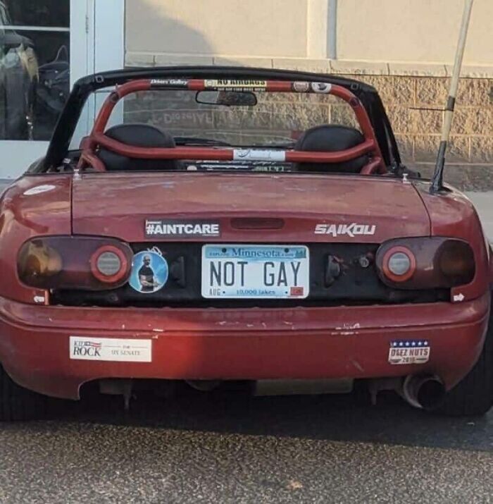 The rear of a red convertible car with a license plate that reads NOT GAY, showing cringy fails.