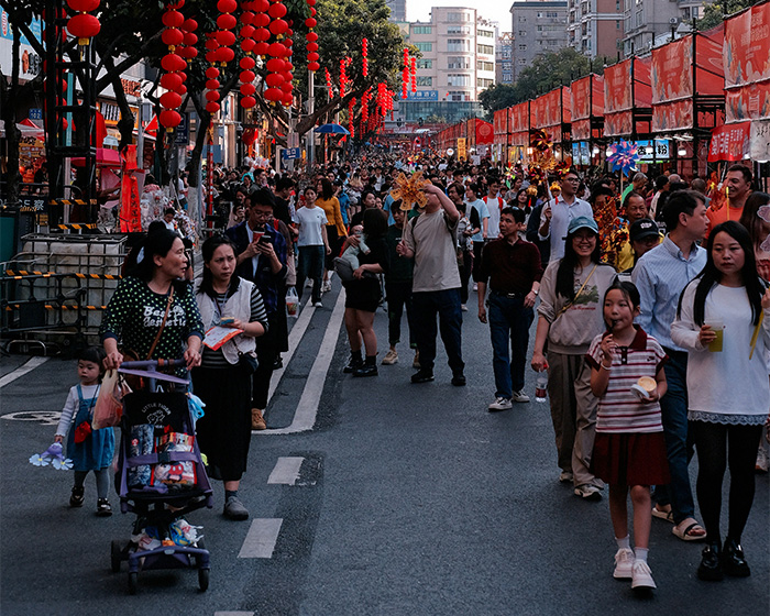 A crowded street with many people and red lanterns. This image represents a public gathering related to a shaming trend.