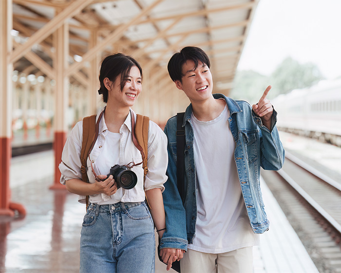 A happy young couple holding hands at a train station. This image reflects a positive view amidst a shaming trend.