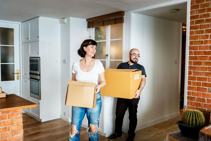 Two clients, a man and a woman, carrying moving boxes, possibly making a stupid move.