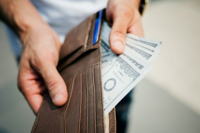 A client opening a wallet full of money, possibly paying lawyers after making stupid financial decisions.