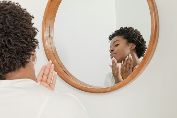 A woman looking in the mirror, noticing skin and facial body changes that happen in her 30s and 40s.
