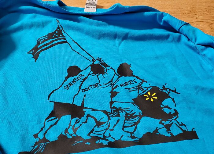 A bright blue shirt with a terrible product design that features a Walmart logo next to doctors, scientists, and nurses.