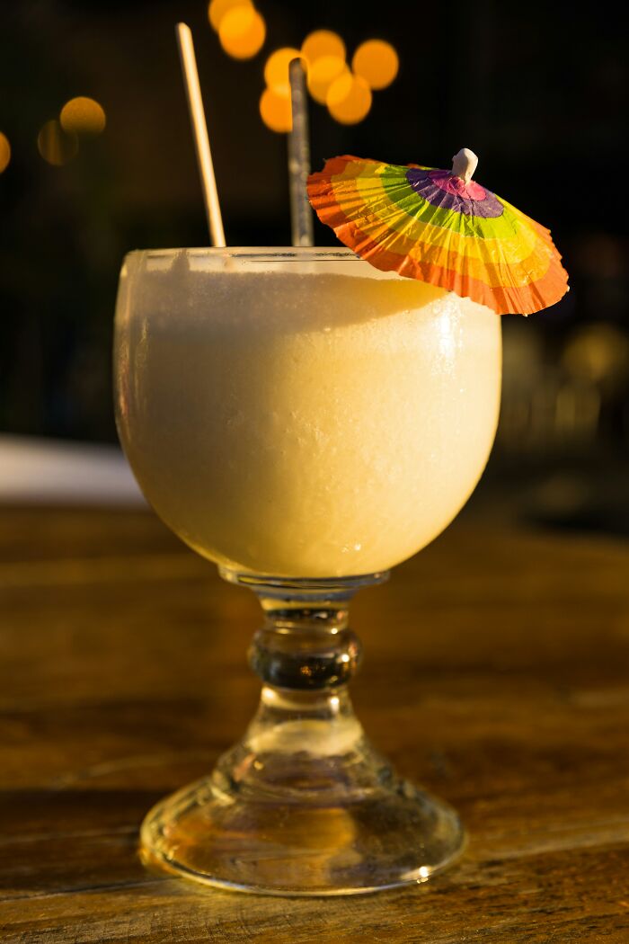 Frozen cocktail with colorful umbrella on wooden table for vacation
