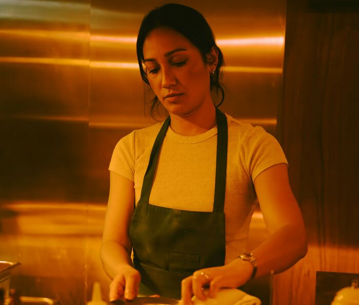 Female cook focused preparing meal in warm kitchen lighting