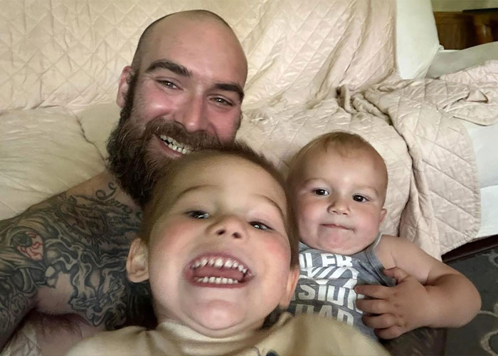 Happy father with a beard and tattoos smiling with his two young children. The children's mother is the attacker. Happy father with a beard and tattoos smiling with his two young children. The children's mother is the attacker.