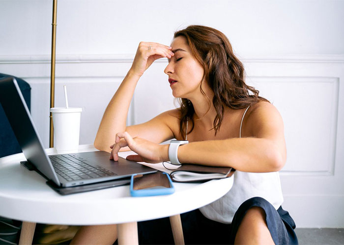 A woman looking stressed at her laptop, representing the bride's frustration over the wedding drama and used gift cards.
