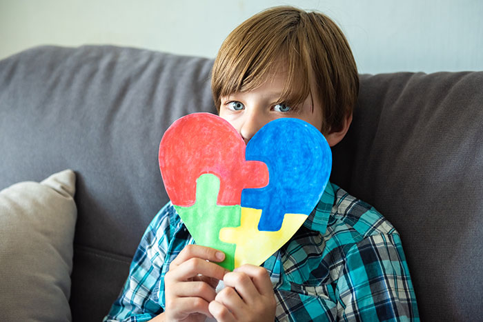 A boy holding a puzzle piece heart, symbolizing the wild delayed plot twists from real lives.