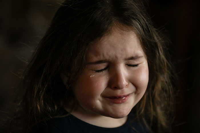 A young girl crying with tears streaming down her face, illustrating unexpected life plot twists.