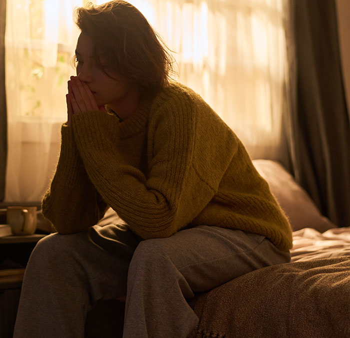 A pensive woman on a bed, illustrating a wild delayed plot twist from life.