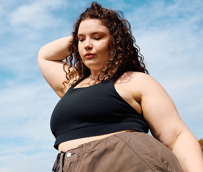 A woman with curly hair looks thoughtful against a bright sky, sharing wild delayed plot twists from her life.