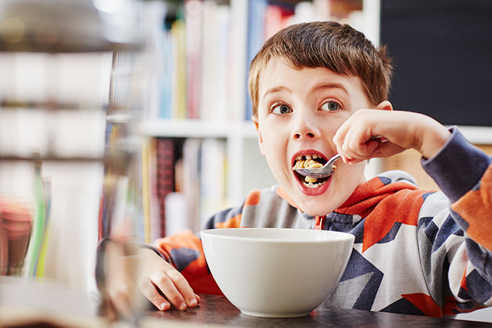 A young boy with brown hair, eating cereal, surprised by an unexpected plot twist from his life.