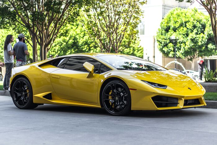 A sleek yellow sports car parked on a city street, a surprising thing wealthy people buy.