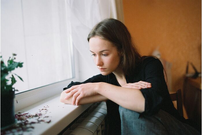 A young woman looking out a window, a child who is finally opening up to a parent.