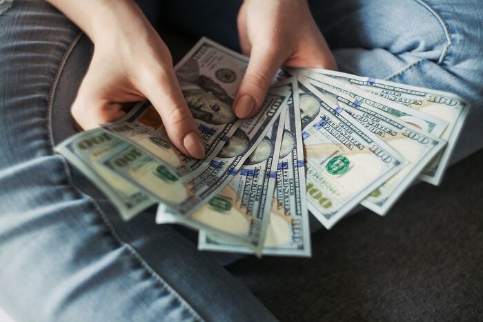 Hands holding fanned-out US dollar bills, depicting the dirty truths and monetary aspects in industries.