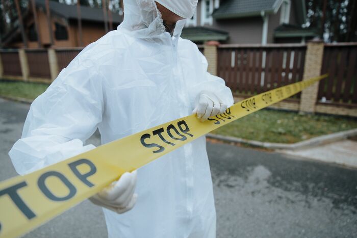 A person in a hazmat suit holding stop tape, symbolizing dirty truths and industry insider regulations.