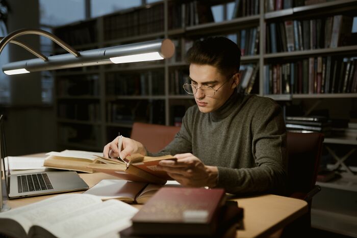 A person studying intensely in a library, illustrating how industry insiders acquire knowledge.