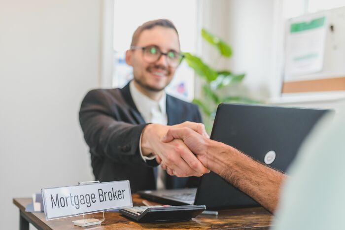 A mortgage broker shaking hands with a client, representing industry insiders and their daily truths.