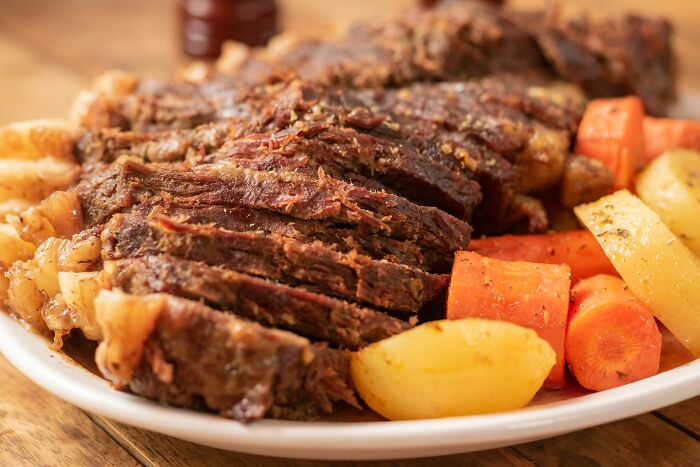 Sliced pot roast with carrots and potatoes, a meal that may hide dirty truths about its preparation.