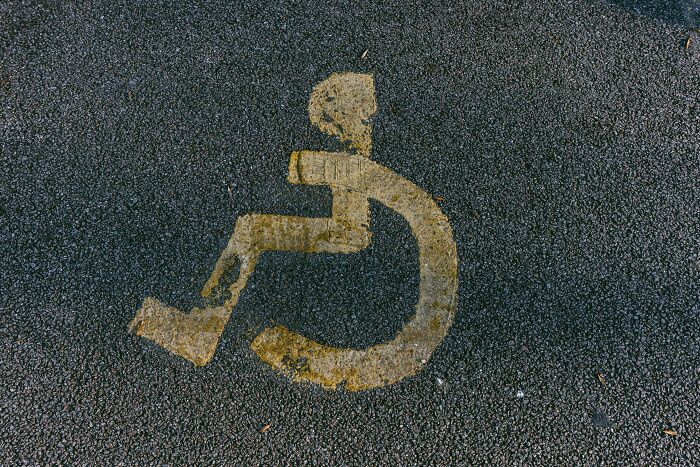 A faded yellow handicap symbol painted on dark asphalt, representing industry insiders facing dirty truths.