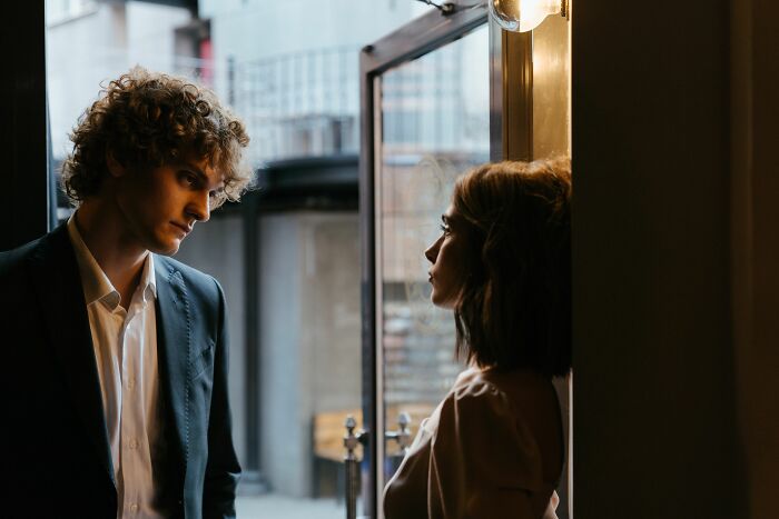 A man in a suit looking at a woman, conveying a serious interaction where industry insiders might reveal dirty truths.