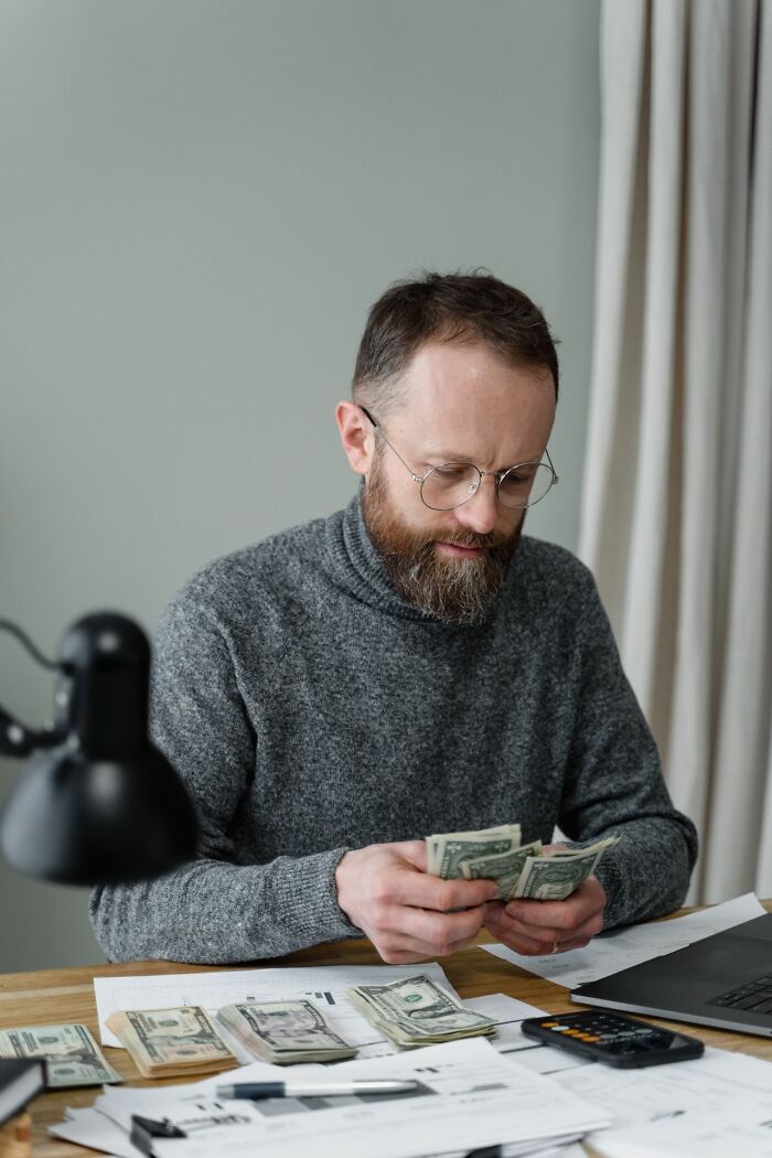 Man counting money at desk reflecting on family cut off financial issues