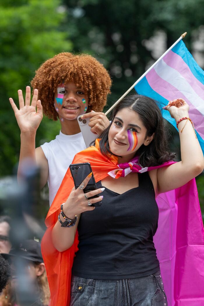 Two people with pride flags symbolizing LGBTQ support amid family estrangement