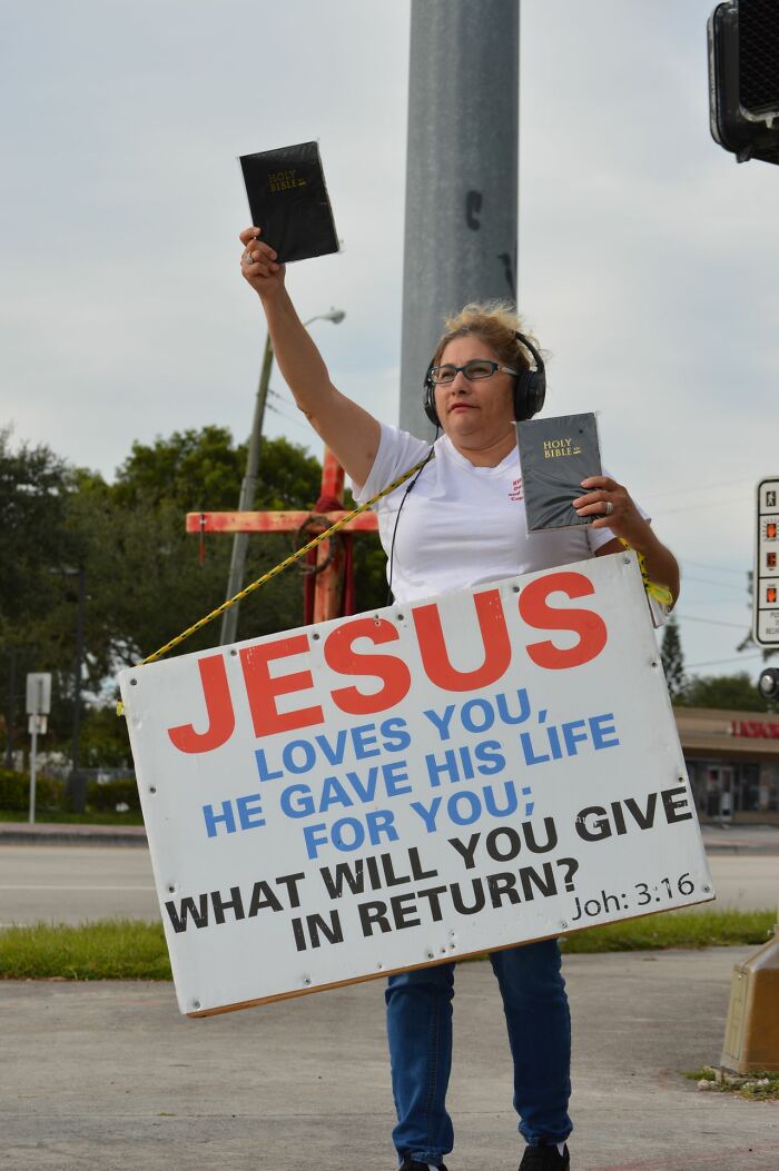 Protester holding Jesus sign and bibles advocating faith during family conflicts