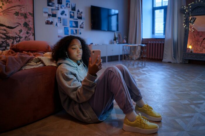 Young woman in hoodie looking at phone feeling isolated from family
