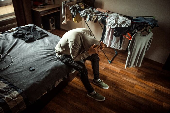 Person sitting alone in bedroom stressed overwhelmed family struggles