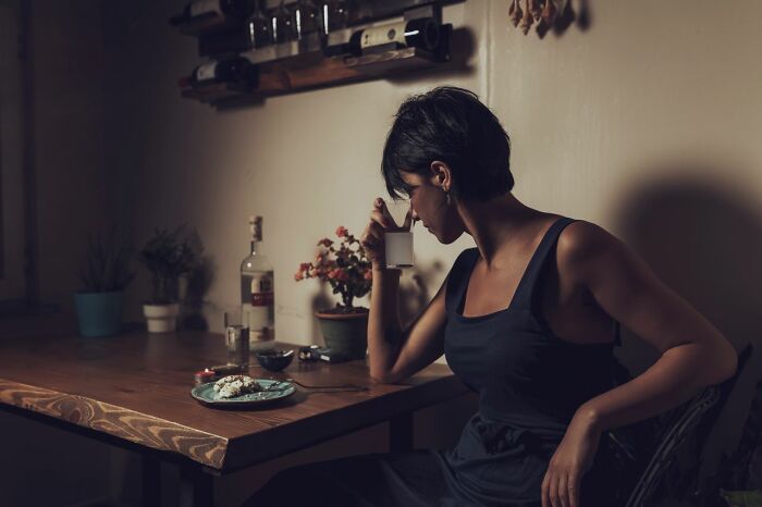 Woman drinking alone at table, symbolizing family cut off pain