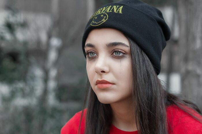 Young woman with teary eyes wearing beanie family cut off reasons