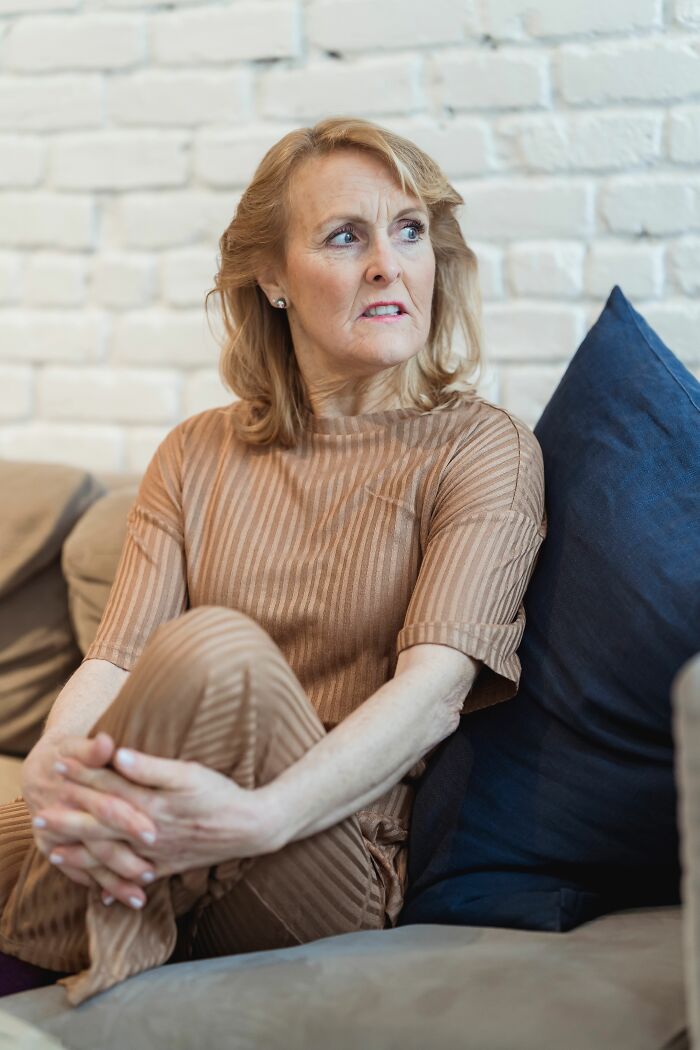 Older woman looking worried on couch, representing painful family cut off reasons