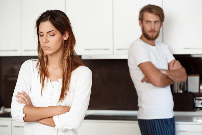 A woman looking upset while a man stands in the background, representing lies men told them.