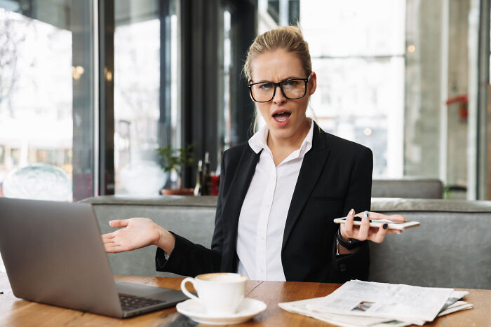 An irritated female professional gestures in frustration, highlighting subtle sexism in office environments.