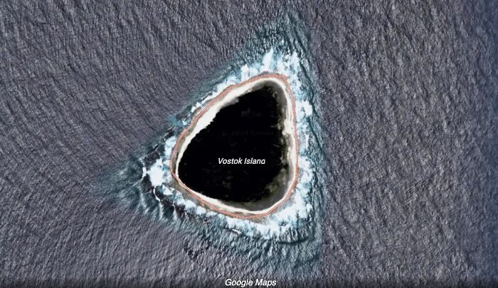 Google Maps view of Vostok Island, a mysterious blacked-out island, revealing its dark, forested appearance.